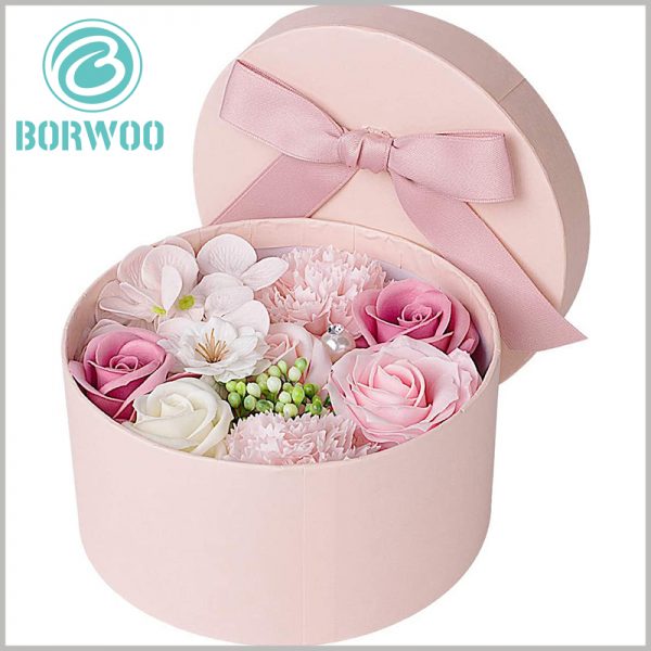 custom cardboard round gift boxes for flowers. There are bows on the top of the pink cardboard round boxes, which play a role in decorating packaging and products.